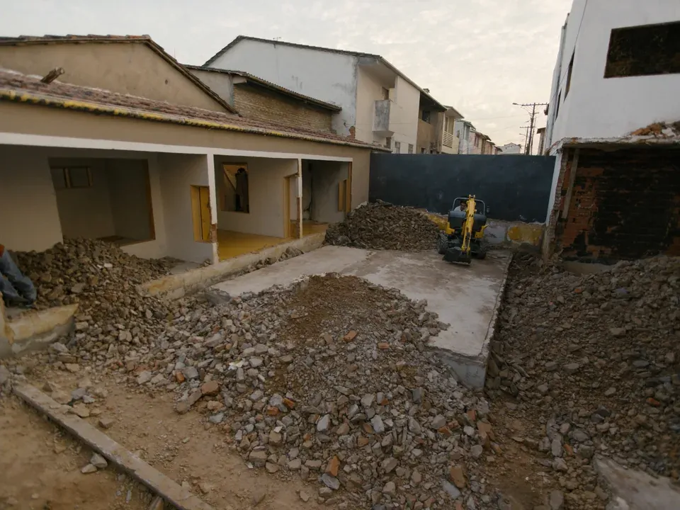 Desmonte manual junto à parede compartilhada, com a casa vizinha preservada