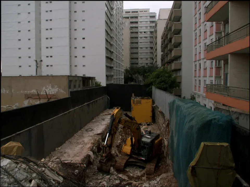 Obra confinada com tapume e edificações ocupadas na divisa